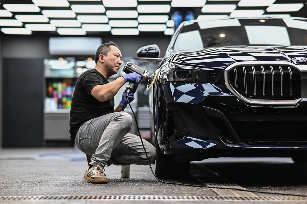 技師蹲姿手持拋光機研磨 BMW 前葉子板，全車已完成前置清潔