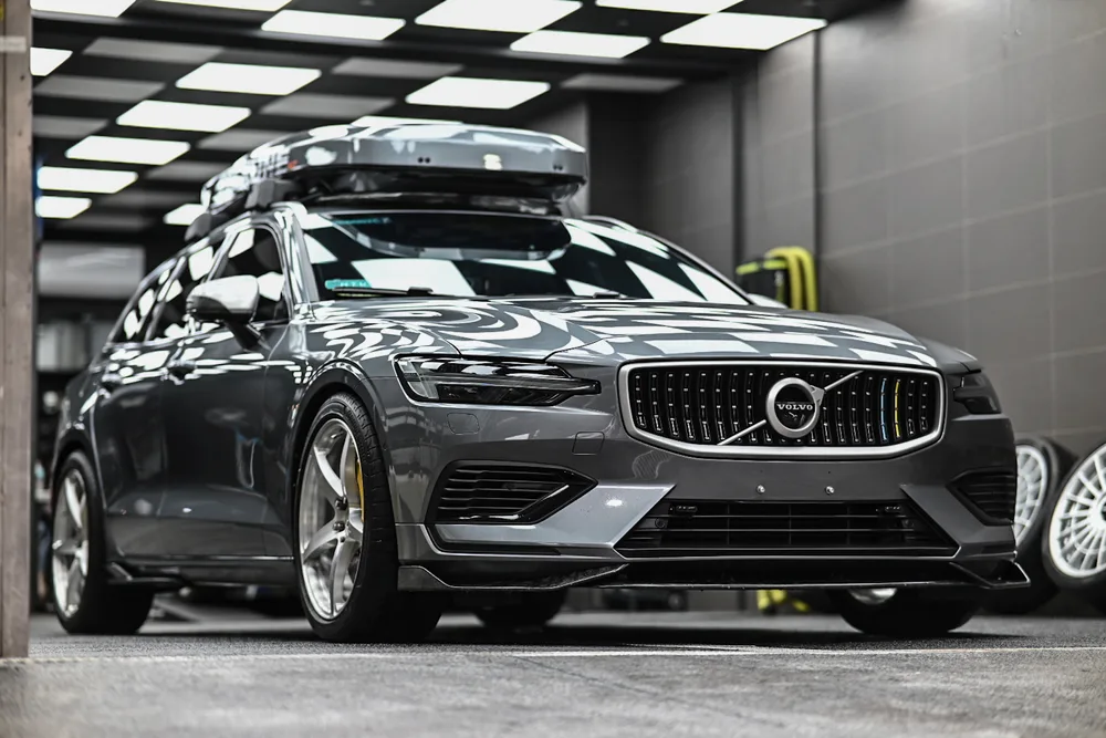 灰色 Volvo V60 旅行車完工停於施工區，車頂行李箱與車身漆面倒影清晰，誠美車體美容