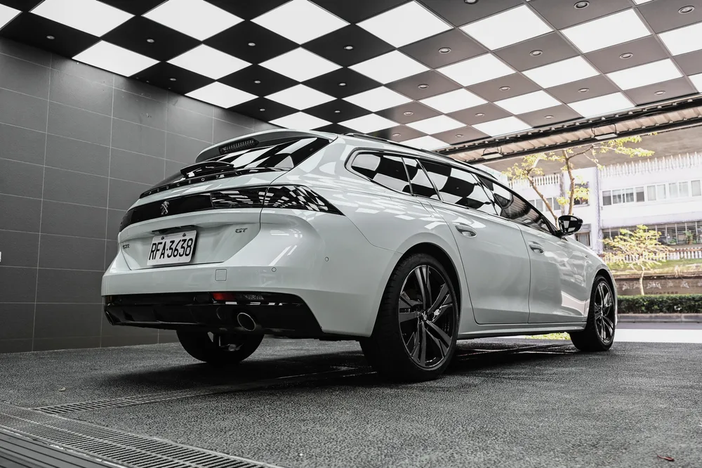 Peugeot 508 SW 左後方全景，尾門與車頂線條在施工區燈光下光澤一致