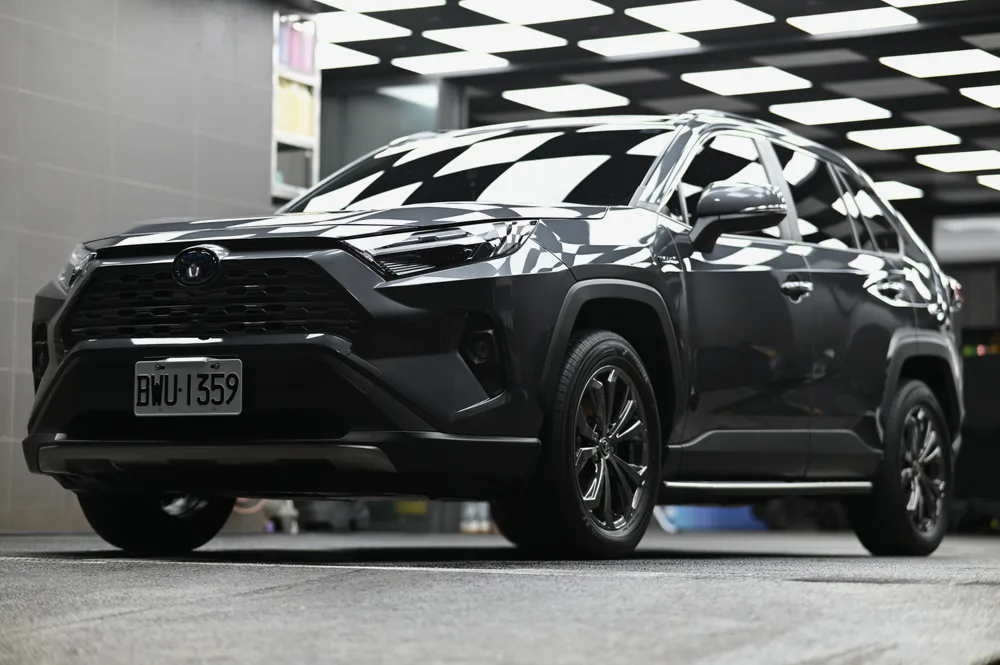 灰色 Toyota RAV4 Hybrid 完成精緻打蠟後停於格紋施工區，車側全景鈑面映出天花板格紋，誠美車體美容