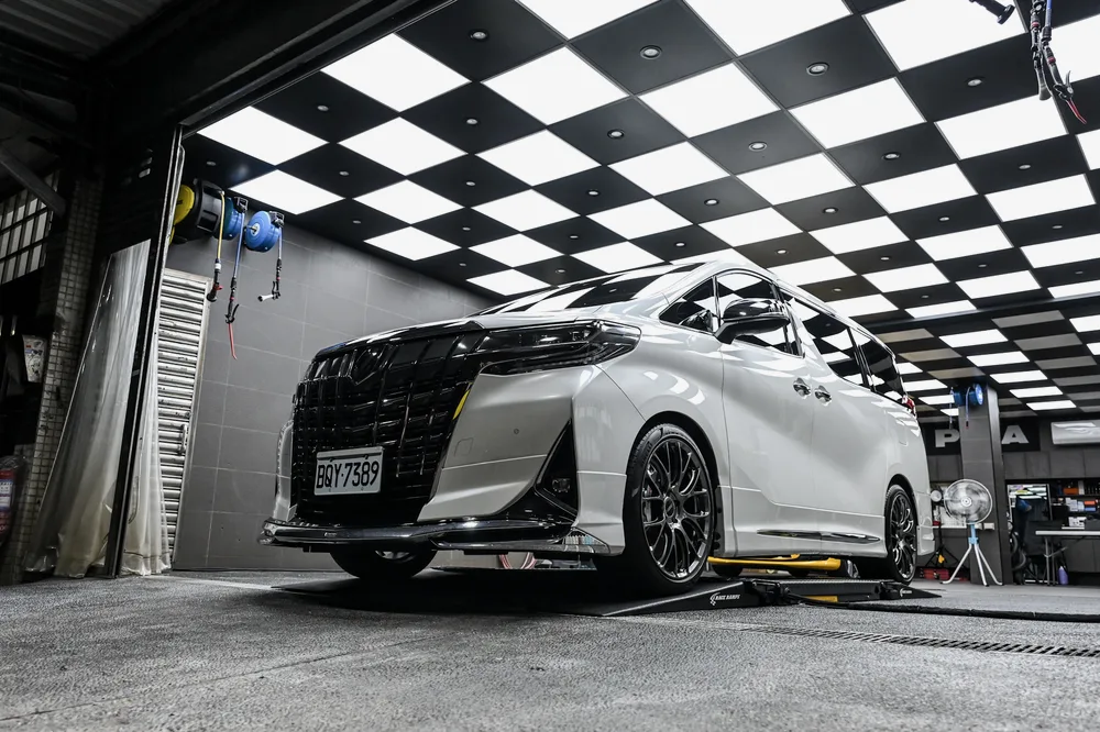 清洗完成的白色 Toyota Alphard 停在施工區，車頭與側裙保持乾淨，誠美車體美容