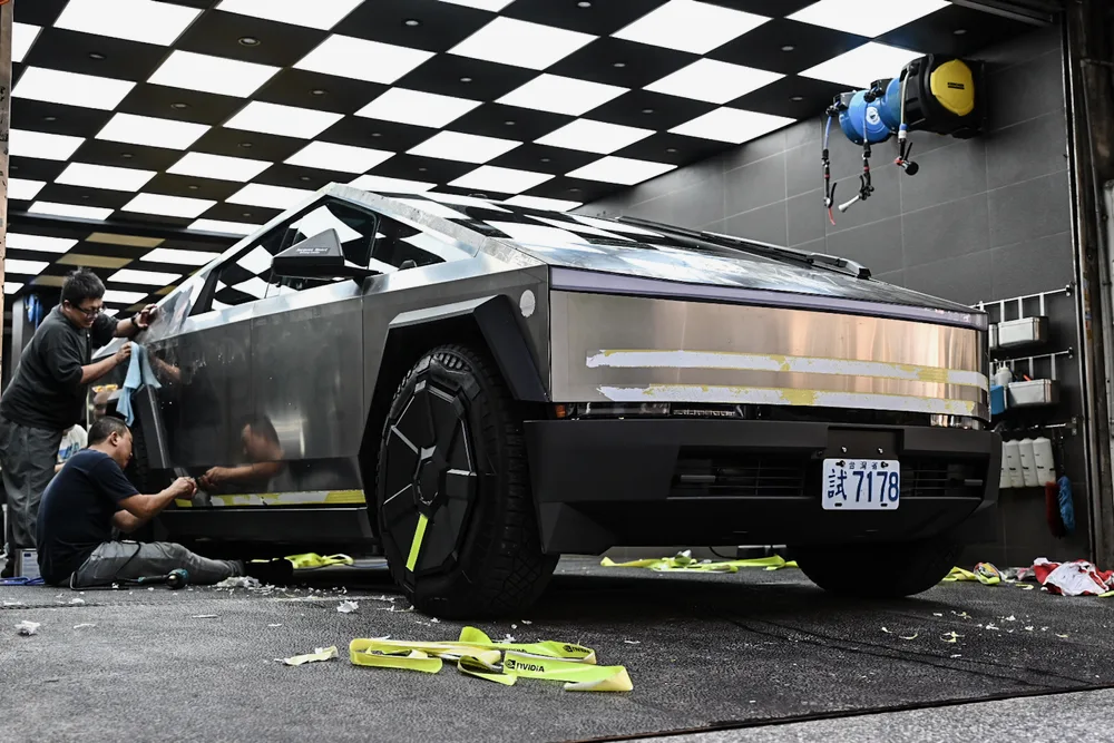 兩位技師合力清除 Tesla Cybertruck 車側殘膠，不鏽鋼板件大面積回復原色，誠美車體美容