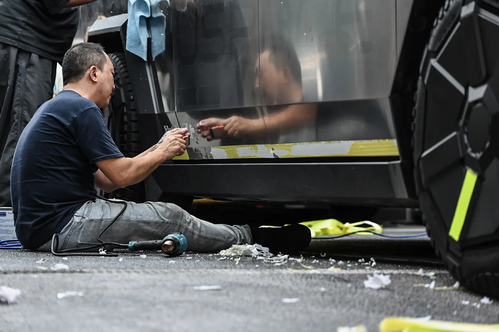 技師坐在地面處理車側下緣，地上散落撕下的貼膜碎片
