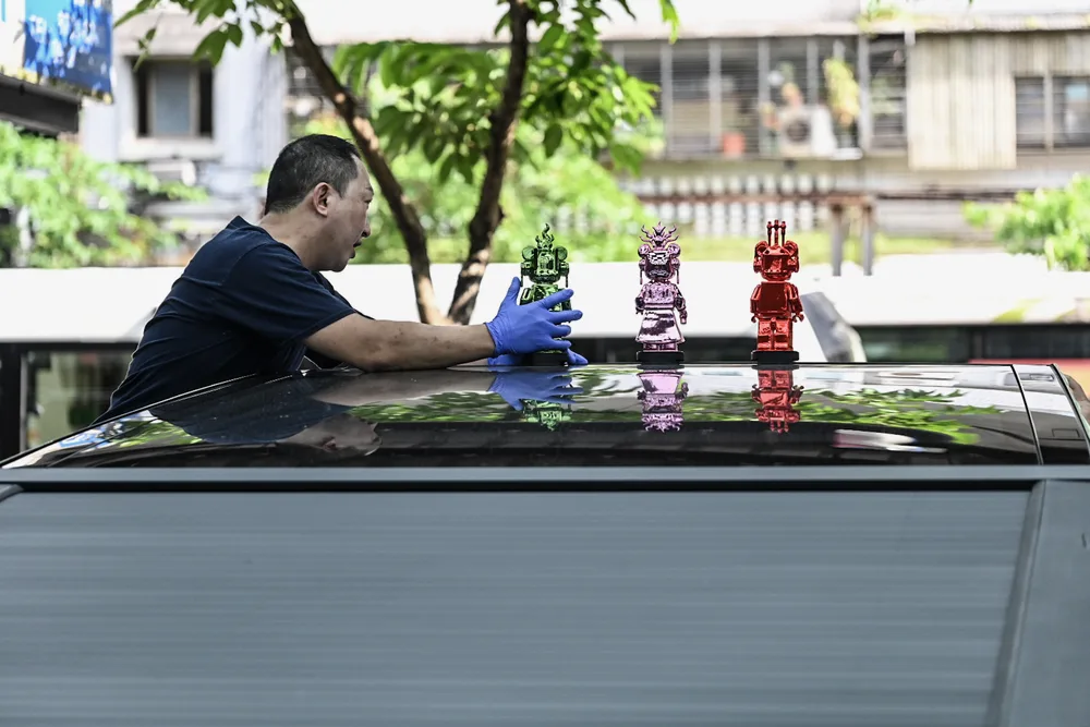 技師以布巾擦拭車斗上蓋，清除作業後的殘留水痕