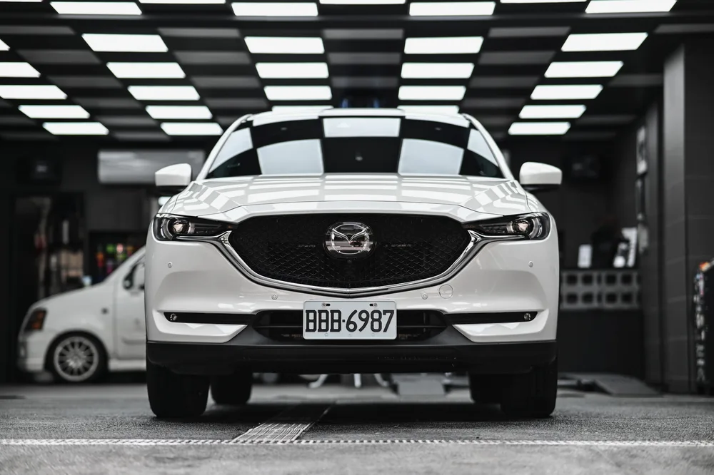 打蠟完工的白色 Mazda CX-5 停在施工區，車頭在燈條下呈現柔亮光澤，誠美車體美容