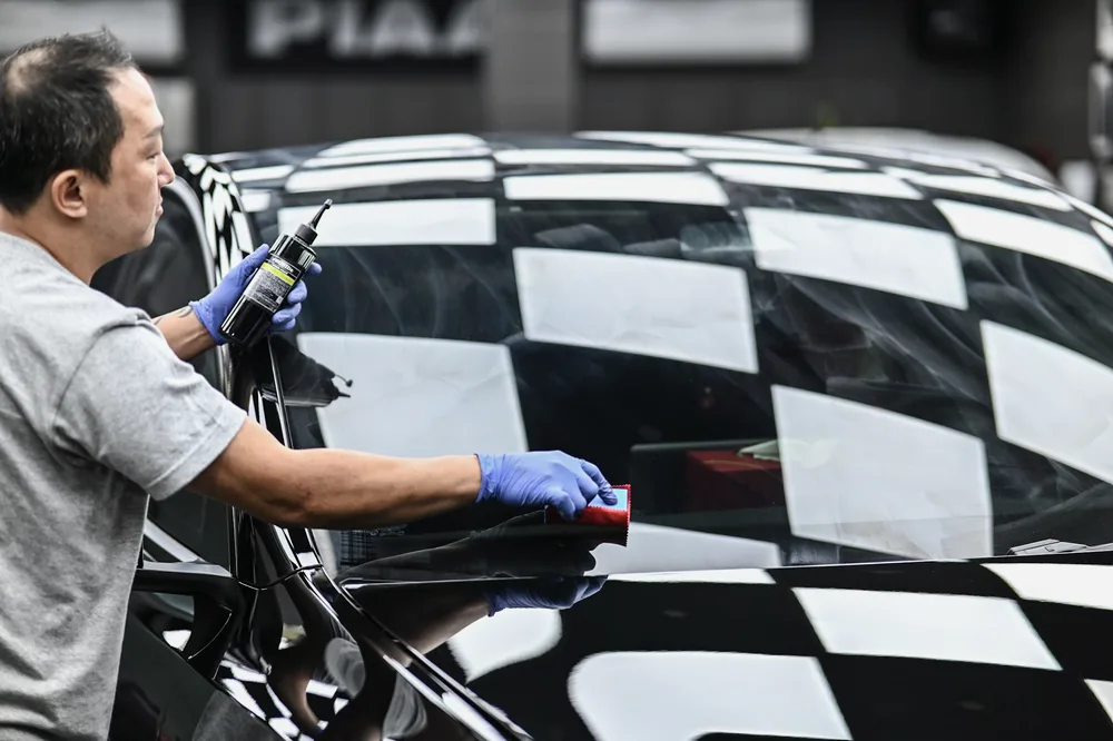 技師以布巾收尾擦拭前擋風玻璃與車頂交界處
