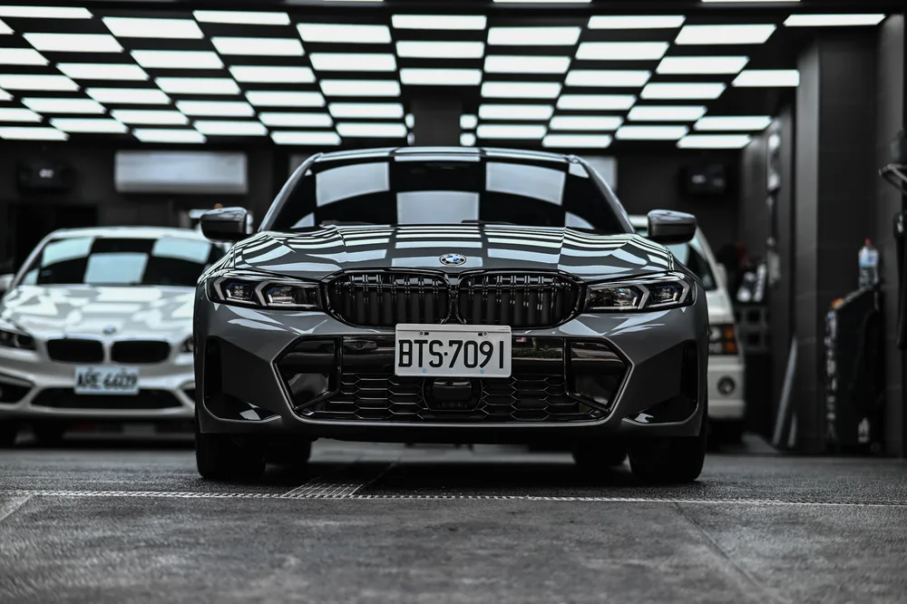 BMW 330i M Sport 灰色車身完成打蠟後的車頭正面，雙腎形水箱罩與引擎蓋線條映出廠內燈條｜誠美車體美容