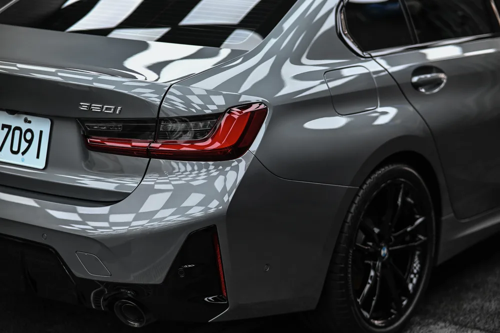 灰色 BMW 3 系列後方四分之三視角，尾燈與後保桿擴散器一併入鏡