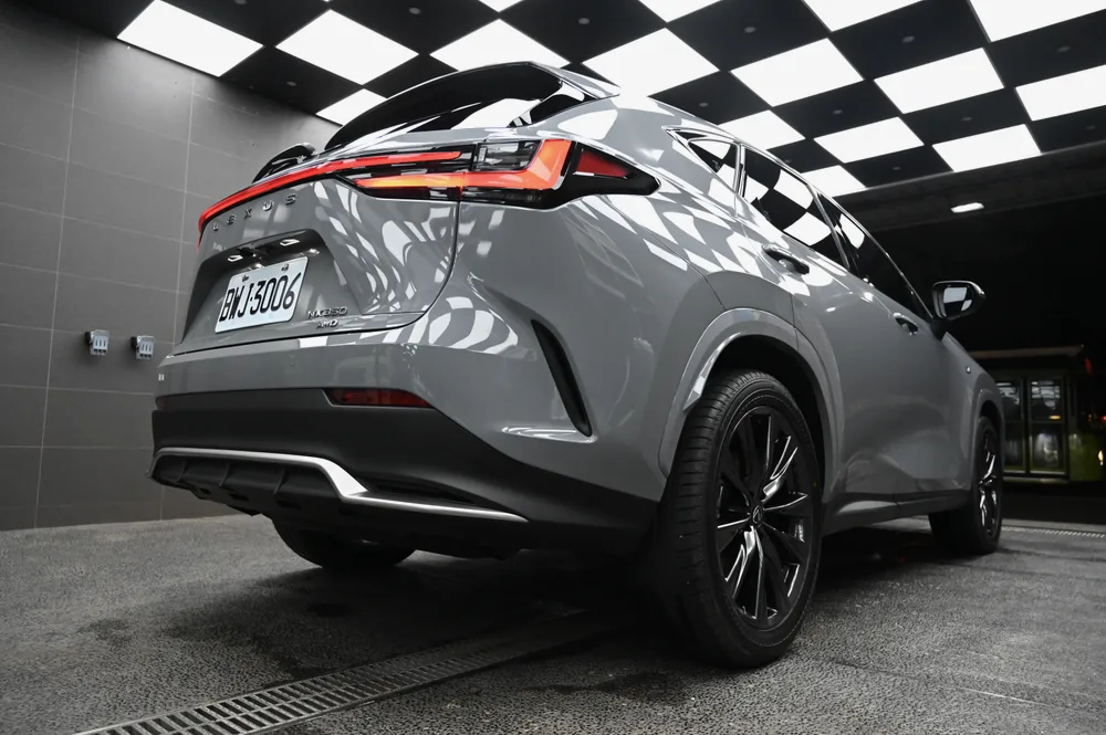 Lexus NX 350 車尾四分之三視角，貫穿式尾燈與後保桿線條在廠內燈光下反射清晰