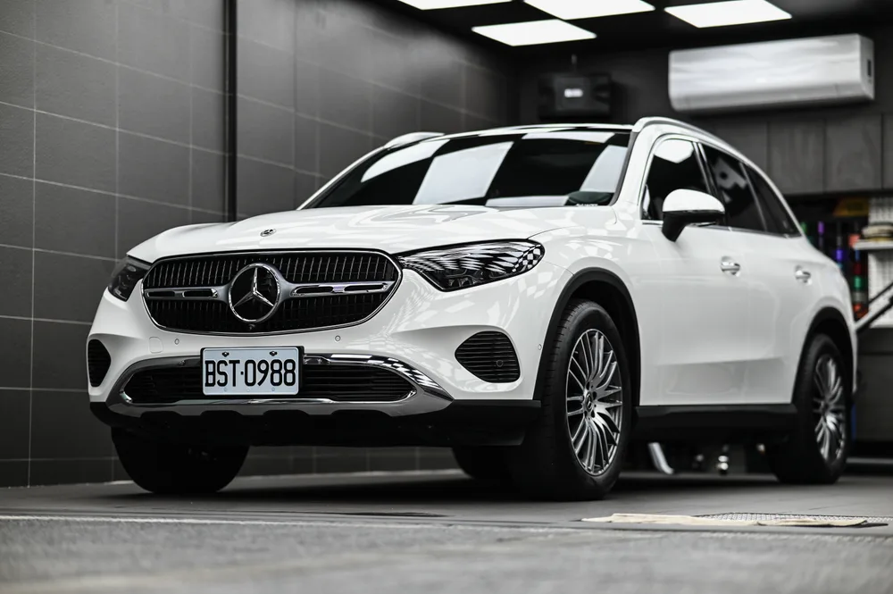 白色 Mercedes-Benz GLC 完成雙層鍍膜後停於施工棚內，右前四十五度全車呈現鏡面光澤，誠美車體美容