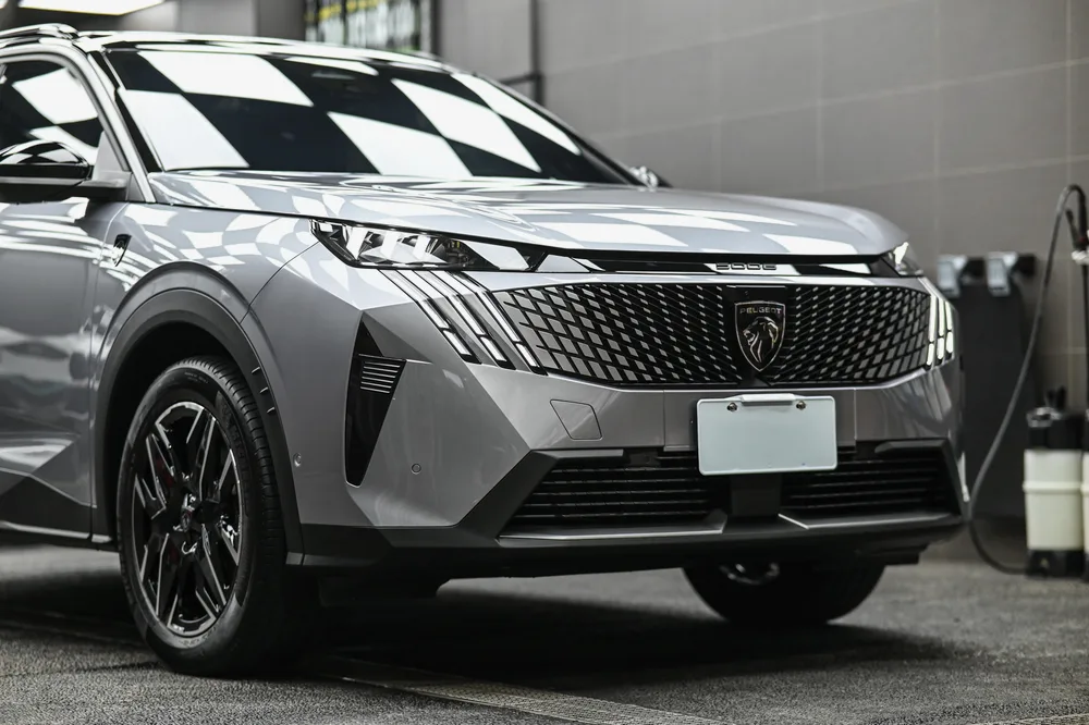 銀灰色 Peugeot 5008 完成車頭迎風面透明保護膜包覆後，停於施工棚內的左前四十五度全車樣貌，誠美車體美容