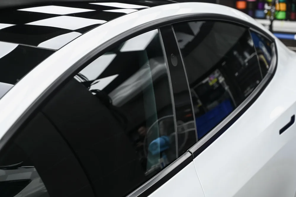 白色 Tesla Model 3 完成全車隔熱紙貼附，於施工棚內呈現的側面車窗色澤，誠美車體美容
