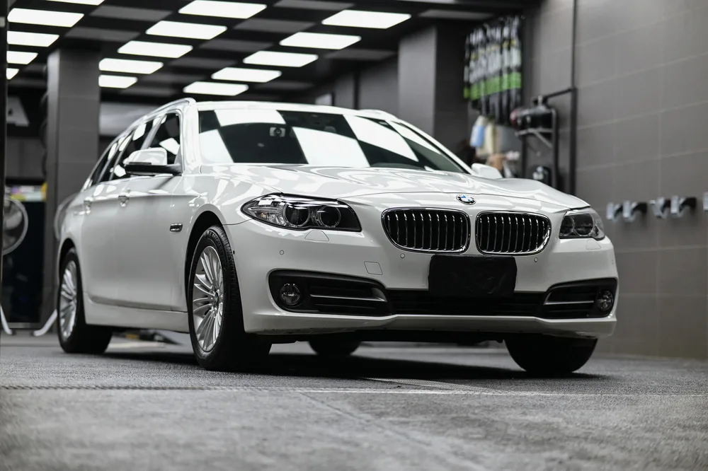 打蠟完工的白色 BMW 520i 停放於施工區，車頭與車側呈現柔和光澤，誠美車體美容