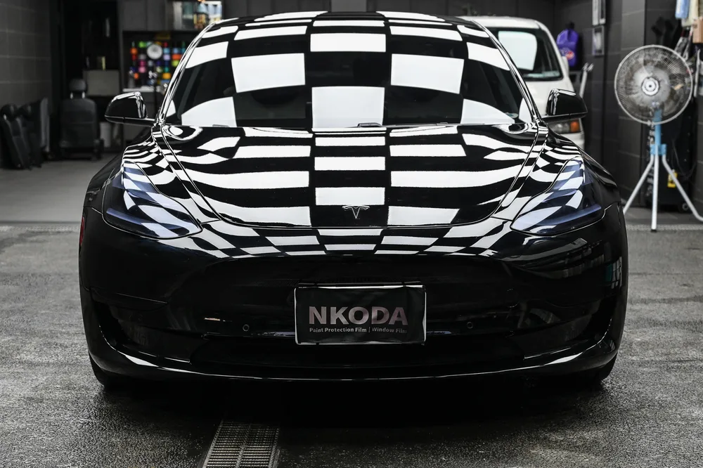 黑色 Tesla Model 3 完成精緻漆面護理後，停於施工棚內的車頭正面光澤，誠美車體美容