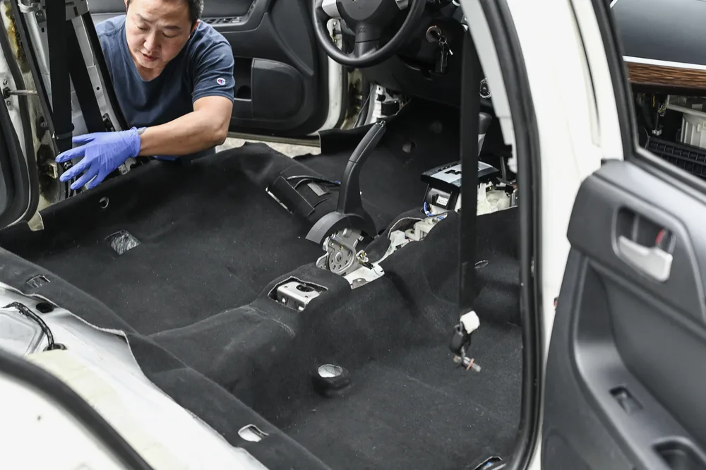 技師戴手套將清洗後的地毯鋪回車室地板並對位固定
