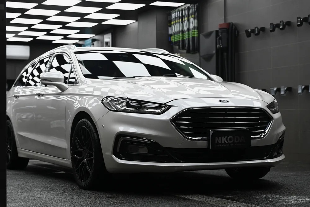 白色 Ford Mondeo 旅行車完工後停在棚內，車頭 45 度角車身線條與漆面光澤完整呈現｜誠美車體美容