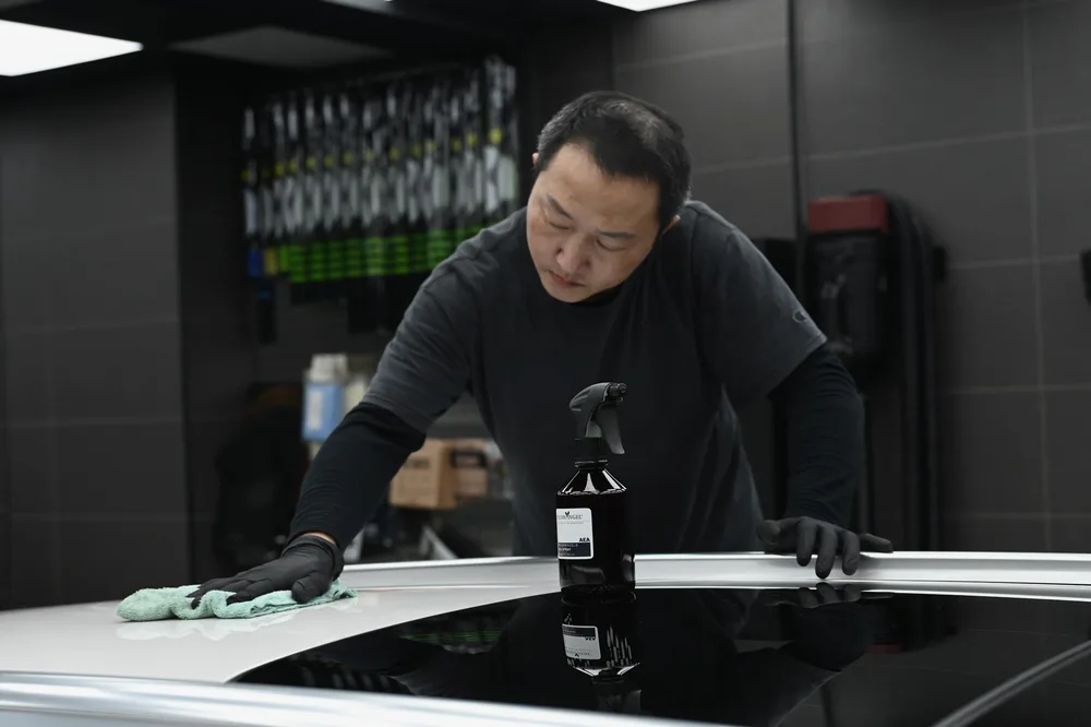 技師伸長手臂擦拭車頂,帶行李架的旅行車頂面逐段收乾