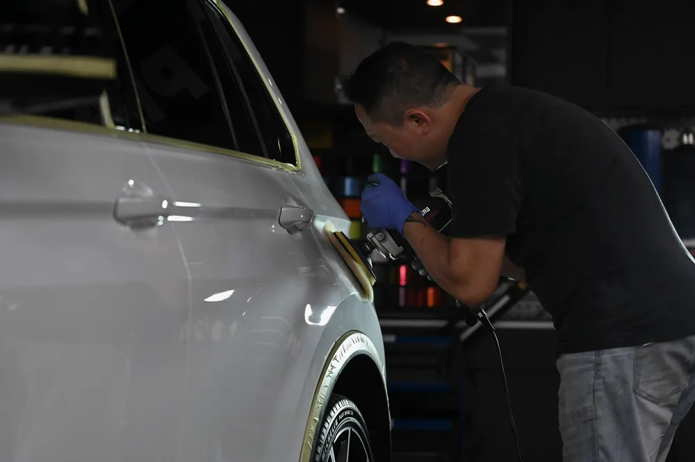 技師俯身拋光前葉子板與車門交界處