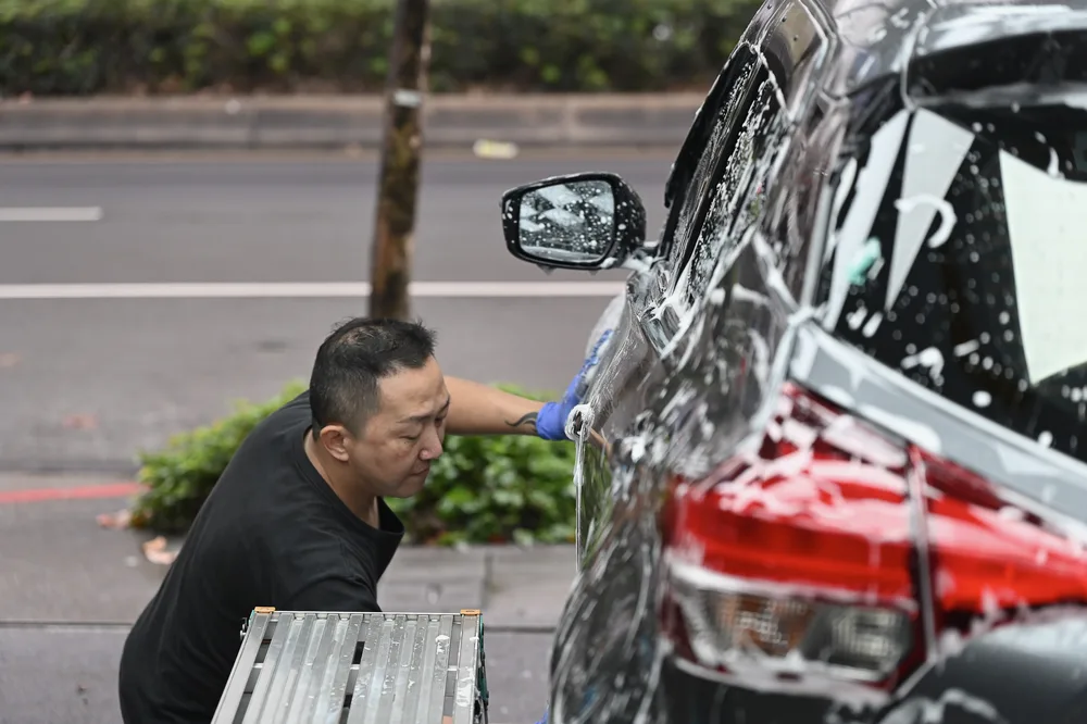 車尾與後車門覆滿清潔泡沫，等待手工洗車程序