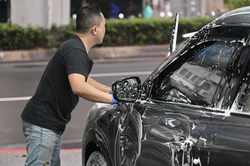 技師以洗車手套沿著車側門板由上而下推開泡沫