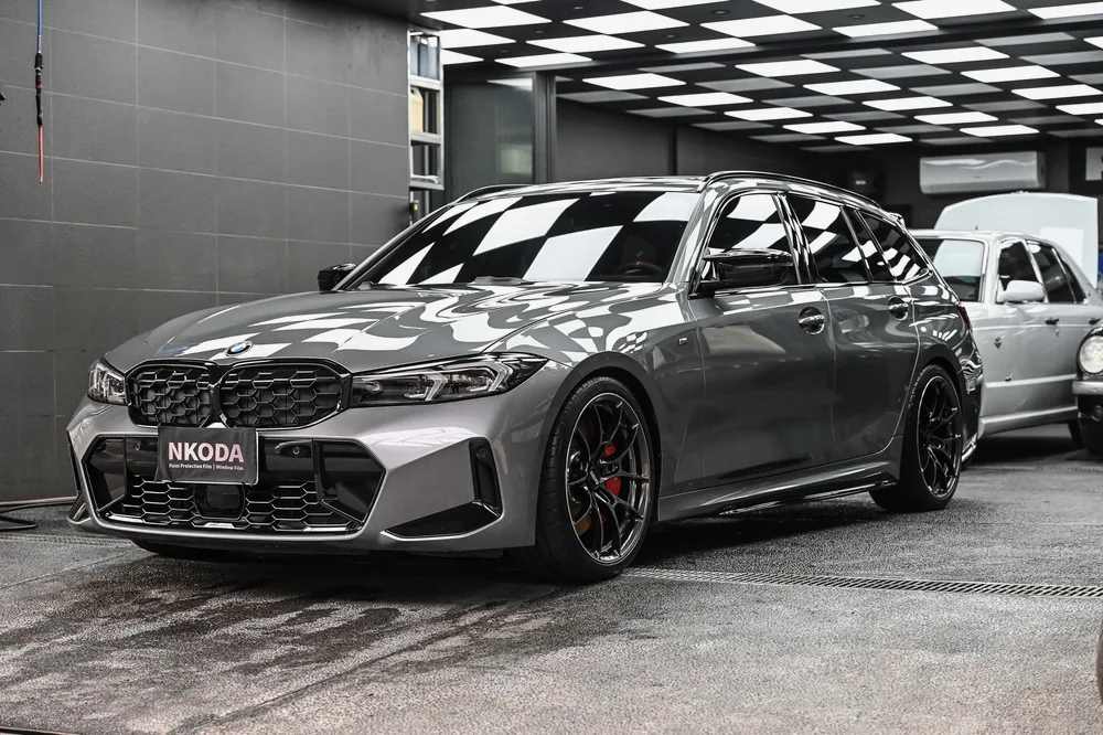 灰色 BMW M3 Touring 完成日本 3D 滑水精緻護理後停於格紋施工區，左前方全景，誠美車體美容