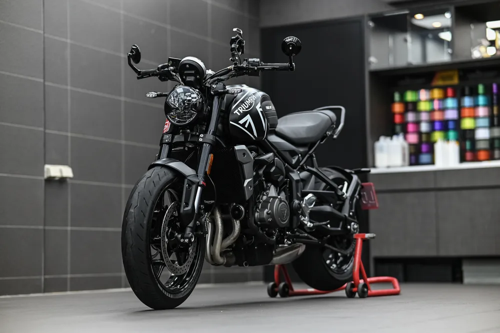 Triumph Trident 重機鍍膜完工後停放於施工區,油箱與前叉呈現均勻黑色光澤,誠美車體美容